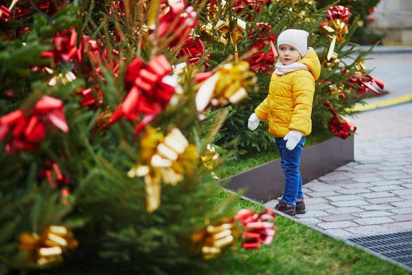 フランスで黄色と赤の弓で飾られたクリスマスツリーの近くの愛らしい未就学児の女の子 子供と一緒に季節の冬の休日を祝う — ストック写真