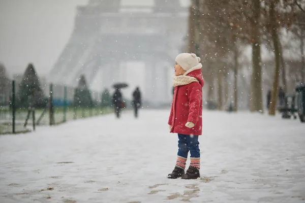 フランスで大雪の日にエッフェル塔の近くの愛らしい幼児の女の子 雪と遊ぶ幸せな子供 子供のための冬の活動 — ストック写真