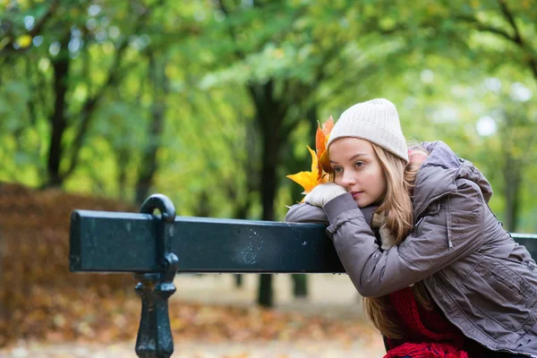 Flicka sitter ensam på bänken på en höst dag — Stockfoto