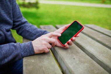 Yeşil ekranlı akıllı telefonu tutan ve kullanan adam