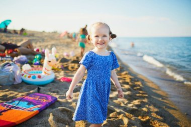 Mavi elbiseli mutlu küçük kız Fransa 'nın Akdeniz sahilinde eğleniyor. Neşeli çocuk denizde tatilin tadını çıkarıyor. Çocuklar için açık hava yaz etkinlikleri
