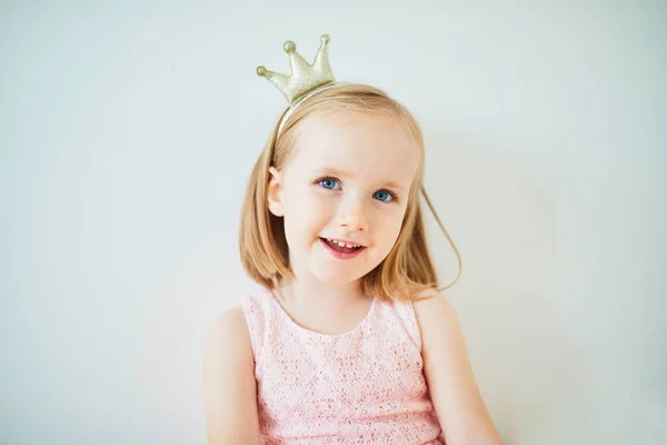 ピンクのドレスとプリンセスに扮した黄金の王冠の愛らしい少女 光を背景にした子供の肖像画 — ストック写真