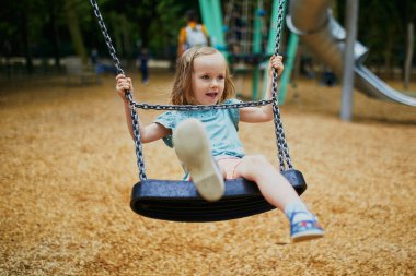 Salıncakta sallanan 4 yaşındaki kızın kutlu olsun. Oyun bahçesinde tahterevallide sallanan mutlu çocuk. Çocuklar için açık hava yaz etkinlikleri