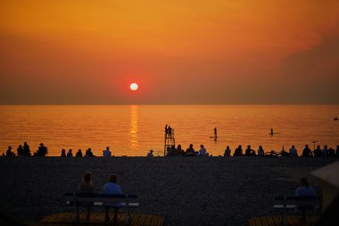 İnsanlar Kuzey Fransa 'da Mers-les-Bains sahilinde gün batımının, Picardy ve Normandiya sınırında küçük bir banyo ve balıkçı köyünün keyfini çıkarıyorlar.