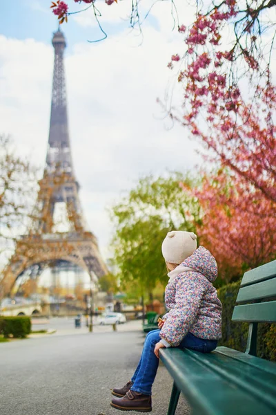 可爱的三岁小女孩坐在法国巴黎埃菲尔铁塔附近的长椅上 在春天的一天 樱桃树在巴黎盛开 — 图库照片
