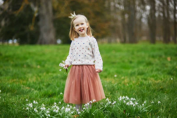 春天的一天 公主王冠上可爱的学龄前姑娘站在草地上 公园或森林里开着许多雪花 小孩在探索自然 儿童的户外活动 — 图库照片