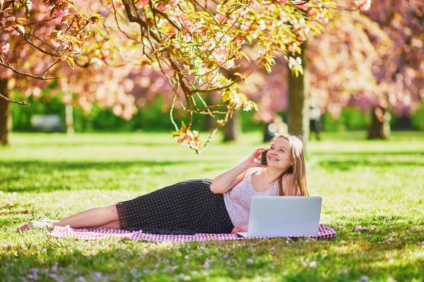 Menina Bonita Trabalhando Seu Laptop Parque Durante Temporada Flor Cerejeira — Fotografia de Stock