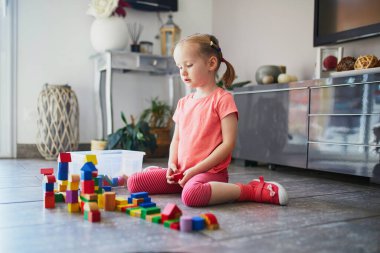 Anaokulunda ya da anaokulunda renkli plastik bloklarla oynayan sevimli küçük bir kız. Çocuklar için yaratıcı oyunlar