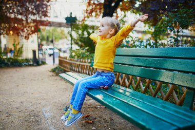 Paris, Fransa 'da bir sokakta bankta oturan üç yaşındaki sevimli bir kız.