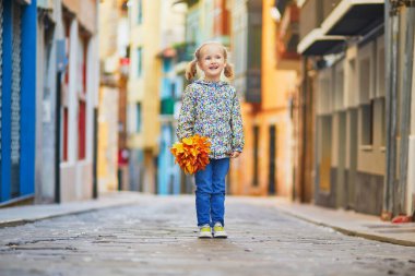 Bermeo, Bask Bölgesi, İspanya 'da bir balıkçı köyünde sonbahar yapraklarıyla dolu mutlu bir kız.