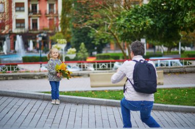 Father taking photo of his daughter on a street of Guernica, Basque Country, Spain. Travelling with kids concept