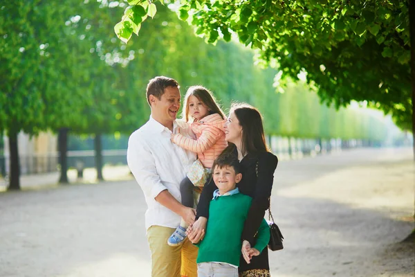 Happy family of four enjoying their trip to Paris, France. Mother, father, son and daughter in Tuileries garden in Paris. Married couple with kids travelling in France