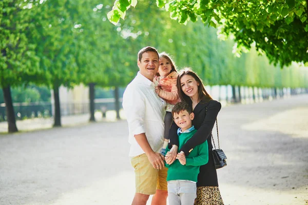 Happy family of four enjoying their trip to Paris, France. Mother, father, son and daughter in Tuileries garden in Paris. Married couple with kids travelling in France