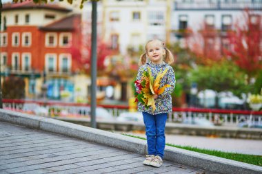 Sevimli anaokulu kızı dışarıda güneşli ve güzel bir sonbahar gününün tadını çıkarıyor. Mutlu çocuk Guernika, İspanya 'da sonbahar yaprakları topluyor. Çocuklar için açık hava sonbahar aktiviteleri