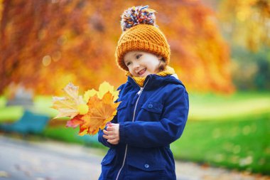 Sevimli anaokulu kızı dışarıda güneşli ve güzel bir sonbahar gününün tadını çıkarıyor. Mutlu çocuk Paris, Fransa 'da sonbahar yaprakları topluyor. Çocuklar için açık hava sonbahar aktiviteleri