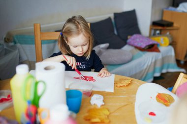 Evde fırça kullanan, anaokulunda ya da anaokulunda resim yapan sevimli küçük bir kız.