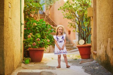 Fransa 'nın Provence kentindeki Bonnieux köyünde beyaz elbiseli ve hasır şapkalı sevimli anaokulu kızı.
