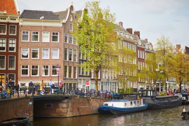 AMSTERDAM, THE NETHERLANDS - MAY 1, 2022: People enjoying nice spring day in Amsterdam with its canals, bridges and boats