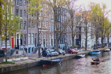 AMSTERDAM, THE NETHERLANDS - MAY 1, 2022: People enjoying nice spring day in Amsterdam with its canals, bridges and boats
