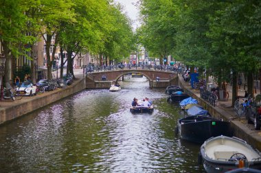 AMSTERDAM, THE NETHERLANDS - AUGUST 18, 2022: People enjoying nice spring day in Amsterdam with its canals, bridges and boats