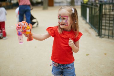 Happy adorable preschooler girl playing with bubbles outdoors on a summer day