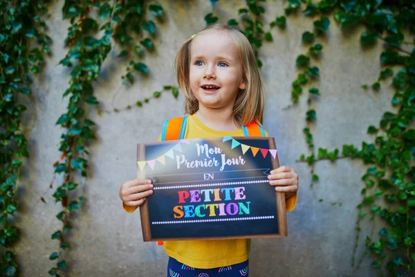 Cheerful 3 years old girl holding a poster with text \