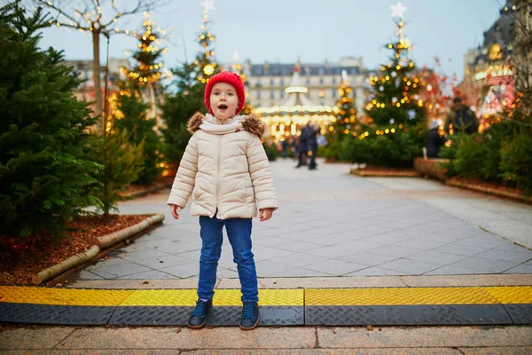 幸せな陽気な就学前の女の子で赤い帽子でクリスマスマーケットでパリ フランス — ストック写真