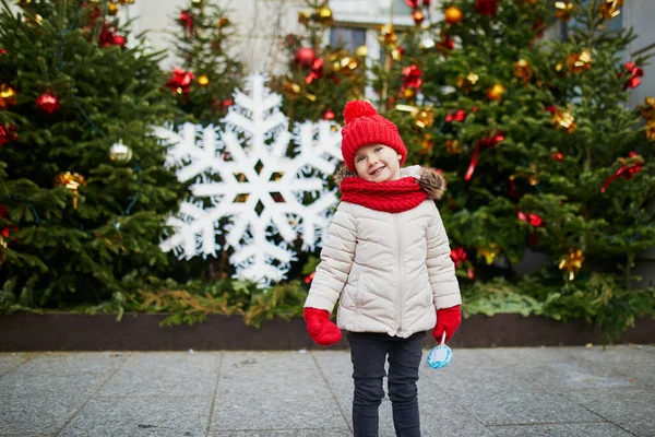 幸せな陽気な就学前の女の子で赤い帽子パリのクリスマスマーケットで楽しんで フランス — ストック写真