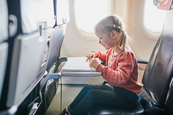 4 year old preschooler girl drawing while travelling by plane