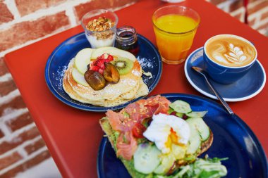 Avokado ve somonlu tost, haşlanmış yumurta, meyveli krep ve akçaağaç şurubu ve Fransa 'nın Kafesi' nde düz beyaz kahve ile nefis sağlıklı bir kahvaltı.