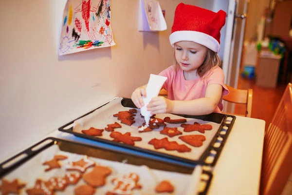 Urocza Przedszkolanka Czerwonym Kapeluszu Mikołaja Gotująca Świąteczne Ciasteczka Świętowanie Wakacji — Zdjęcie stockowe