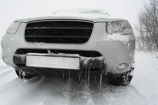 雪に覆われた田舎道につららのある大きな灰色の車 — ストック写真