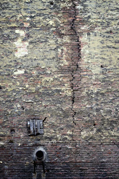 Vieux mur de briques avec une fissure et un tuyau — Photo