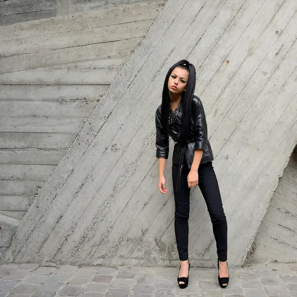 Mooie brunette met lange haren tegen een betonnen muur — Stockfoto
