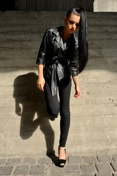 Mooie brunette met lange haren tegen een betonnen muur — Stockfoto