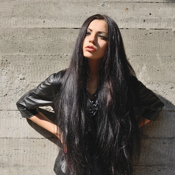Linda morena com cabelos longos contra uma parede de concreto — Fotografia de Stock