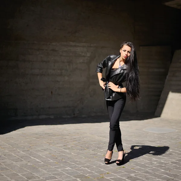 Belle brune aux cheveux longs contre un mur en béton — Photo