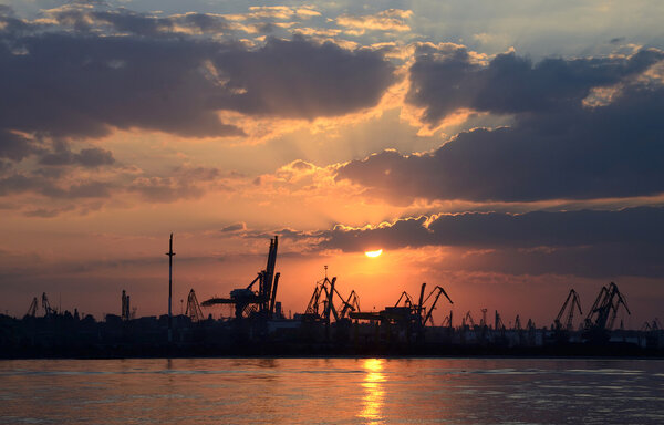 Закат с силуэтами грузовых кранов в Одесском порту, Черное море
