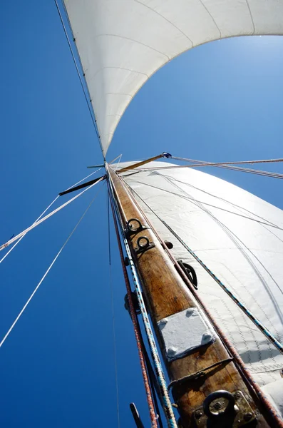 Old wooden mast and white sail, view from deck of boat — Stock Photo, Image