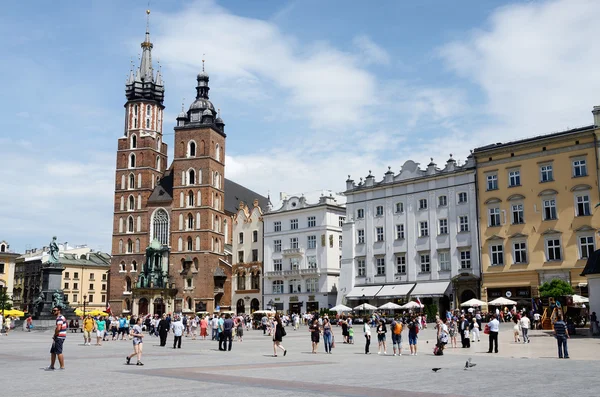 Turistas visitando a praça principal do mercado em frente à Basílica de Santa Maria, em Cracóvia, Polônia — Fotografia de Stock