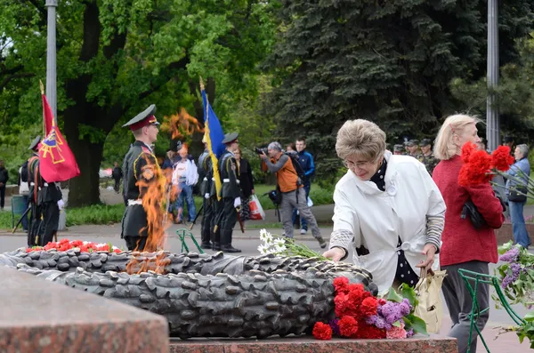 Γριά Βάλτε τα λουλούδια σε αιώνια φλόγα στον εορτασμό των Σοβιετικών στρατιωτών που πολέμησαν κατά τη ναζιστική εισβολή κατά τη διάρκεια Δεύτερος παγκόσμιος πόλεμος, Οδησσός, Ουκρανία — Φωτογραφία Αρχείου