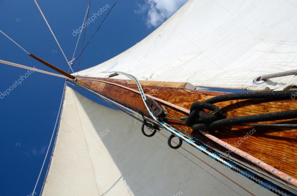 Old wooden mast with crosspieces, backstays,mainsail and staysail, view from deck of boat