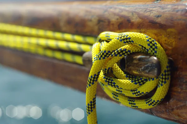 Gros plan de vieux crampon vintage avec ligne jaune sur yacht en bois, outil pour garder les cordes serrées — Photo