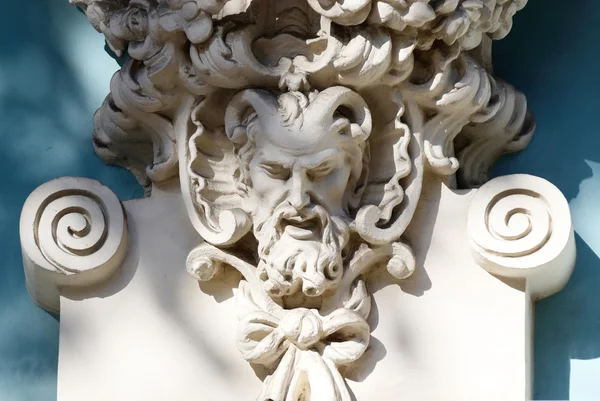 Horned head of Satyr,old house decoration.In Greek mythology,it  is one of a troop of ithyphallic male companions of Dionysus with horse-like features — Stock Photo, Image