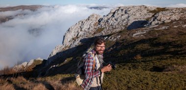 Genç adam bir dağda dijital kamerayla fotoğraf çekiyor..