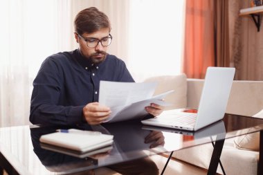 Girişimci bir dizüstü bilgisayarla çalışır ve bir belgeyi ev ofisinde saklar