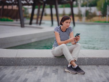 Parkta akıllı telefonlu genç bir kadının portresi