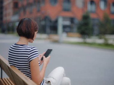 Sokakta cep telefonu kullanan gülümseyen kadın.