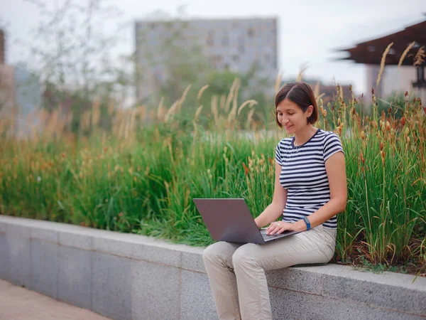 Женщина работает с ноутбуком в современном университетском городском парке. — стоковое фото