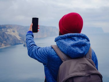 Kadın akıllı telefondan denizin fotoğrafını çekiyor.